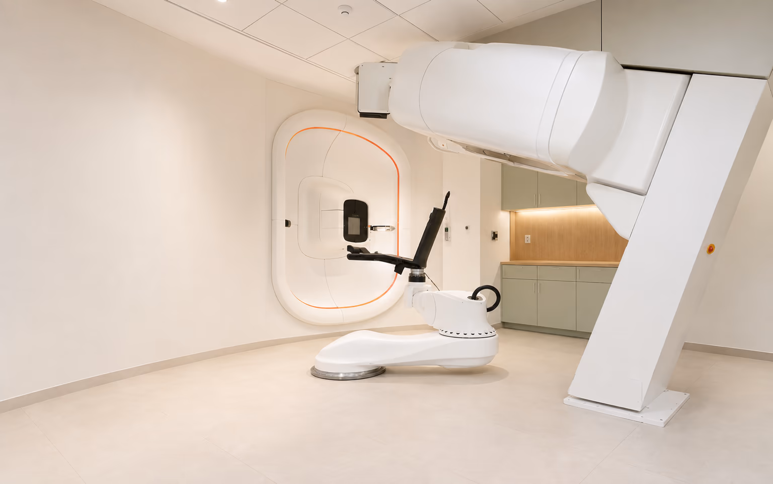 Aristion’s P-Cure room, with a fixed wall-mounted proton beam unit, robotic upright chair and raised CT scanner.
